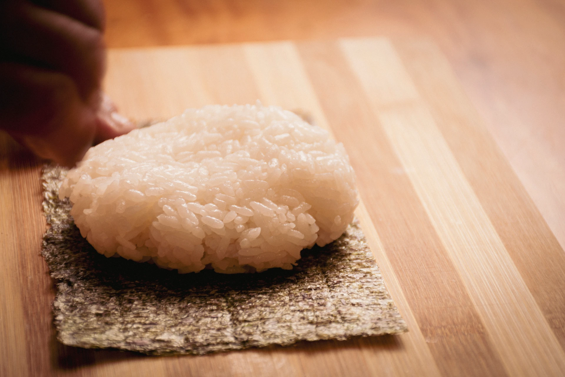 Fotografía gastronómica de porción de arroz de sushi colocada sobre hoja de nori en tabla de bambú — Jose Fonseca Medellín