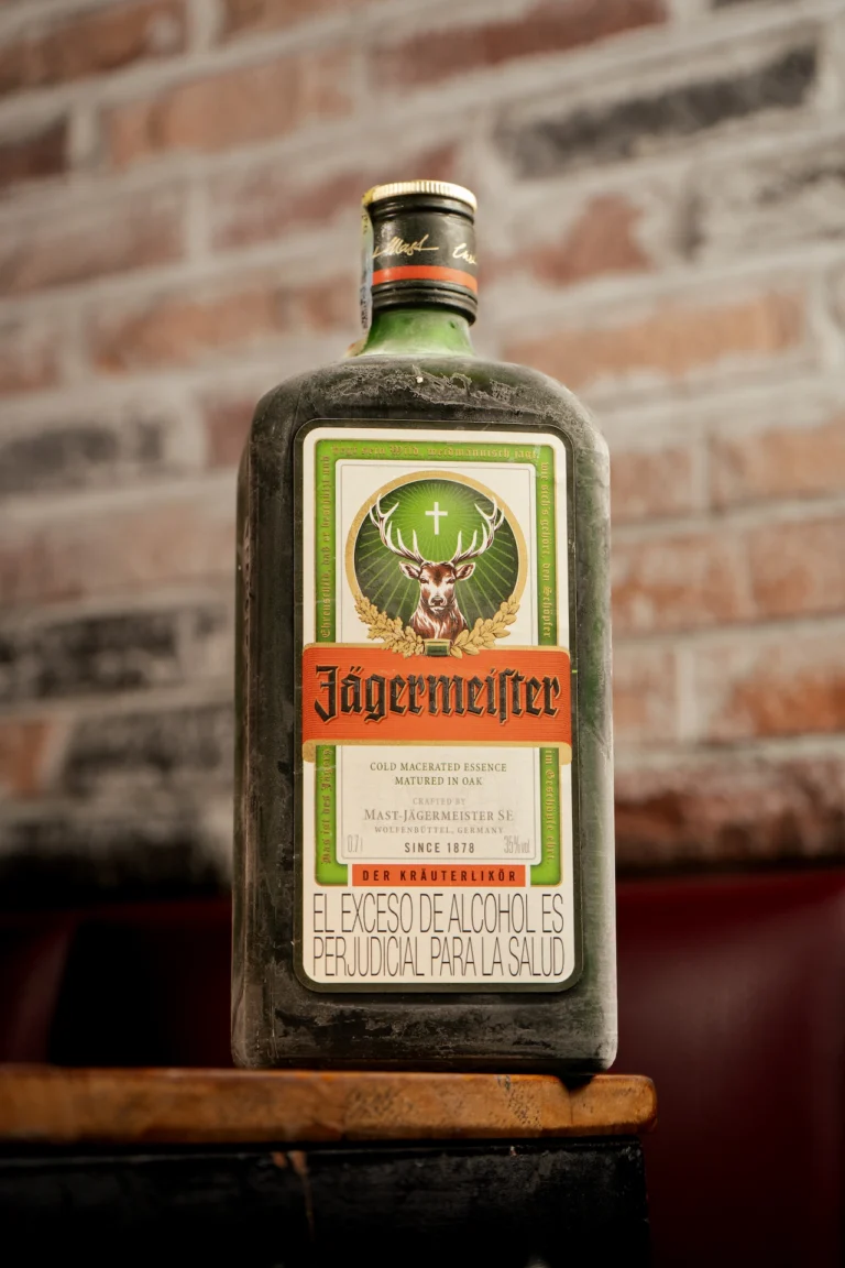 Fotografía gastronómica de botella Jägermeister sobre madera con pared de ladrillo expuesto — Jose Fonseca Medellín