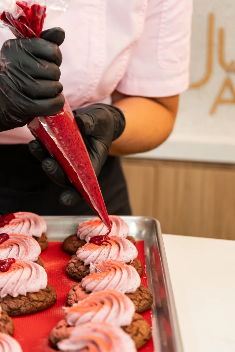 Fotografía gastronómica de chef decorando cookies con manga pastelera de frambuesa en Juliana Postres Medellín — Jose Fonseca