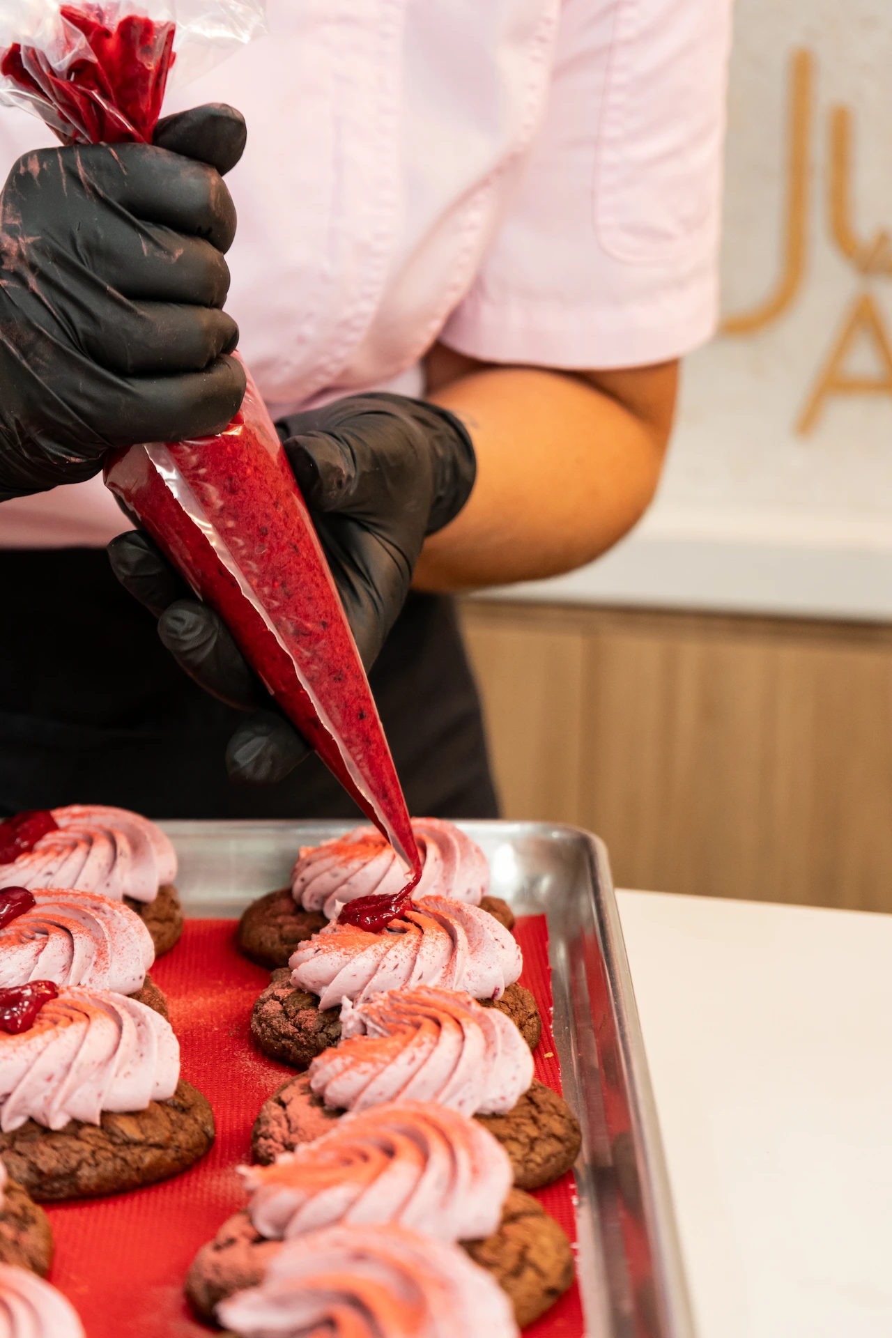 Fotografía gastronómica de chef decorando cookies con manga pastelera de frambuesa en Juliana Postres Medellín — Jose Fonseca