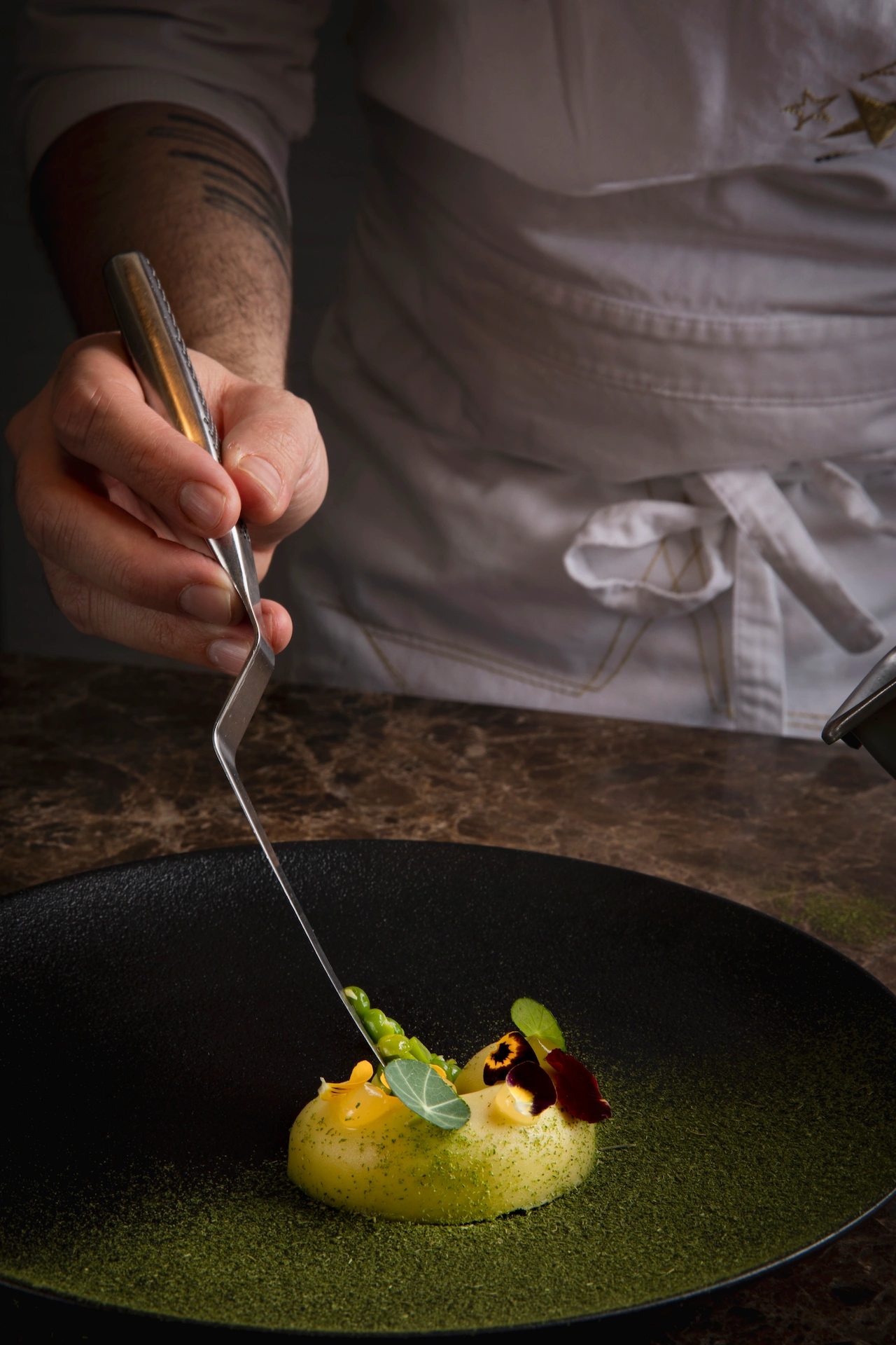 Fotografía gastronómica de chef emplatando postre con polvo de matcha en plato negro de alta cocina — El Cielo Restaurant Medellín
