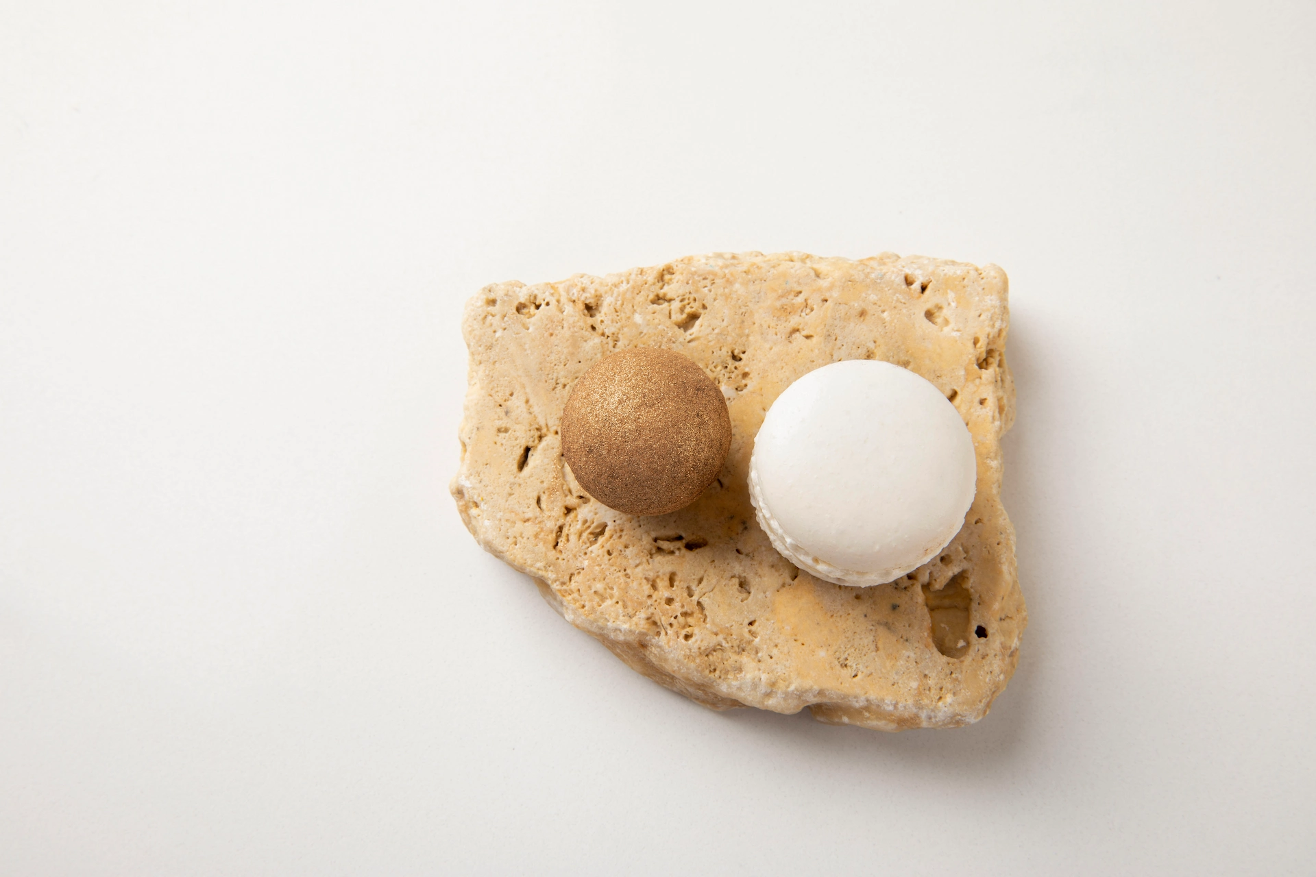 Fotografía gastronómica conceptual de esferas dorada y blanca sobre piedra travertino en alta cocina creativa — Jose Fonseca Medellín