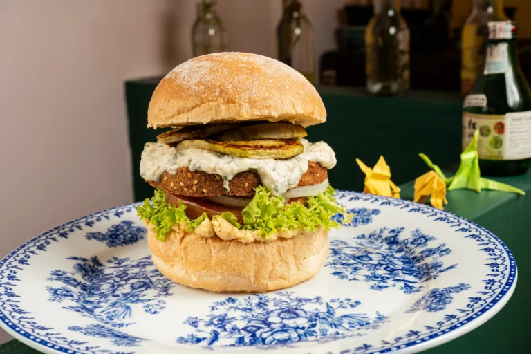 Fotografía gastronómica de hamburguesa vegana con paty de falafel, pepino grillado y salsa tzatziki en plato porcelana azul — Jose Fonseca Medellín