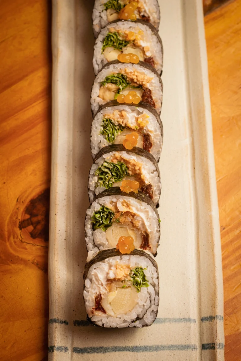 Fotografía gastronómica cenital de maki vegano con hoja de nori, relleno vegetal y esferas naranjas en bandeja — Jose Fonseca Medellín