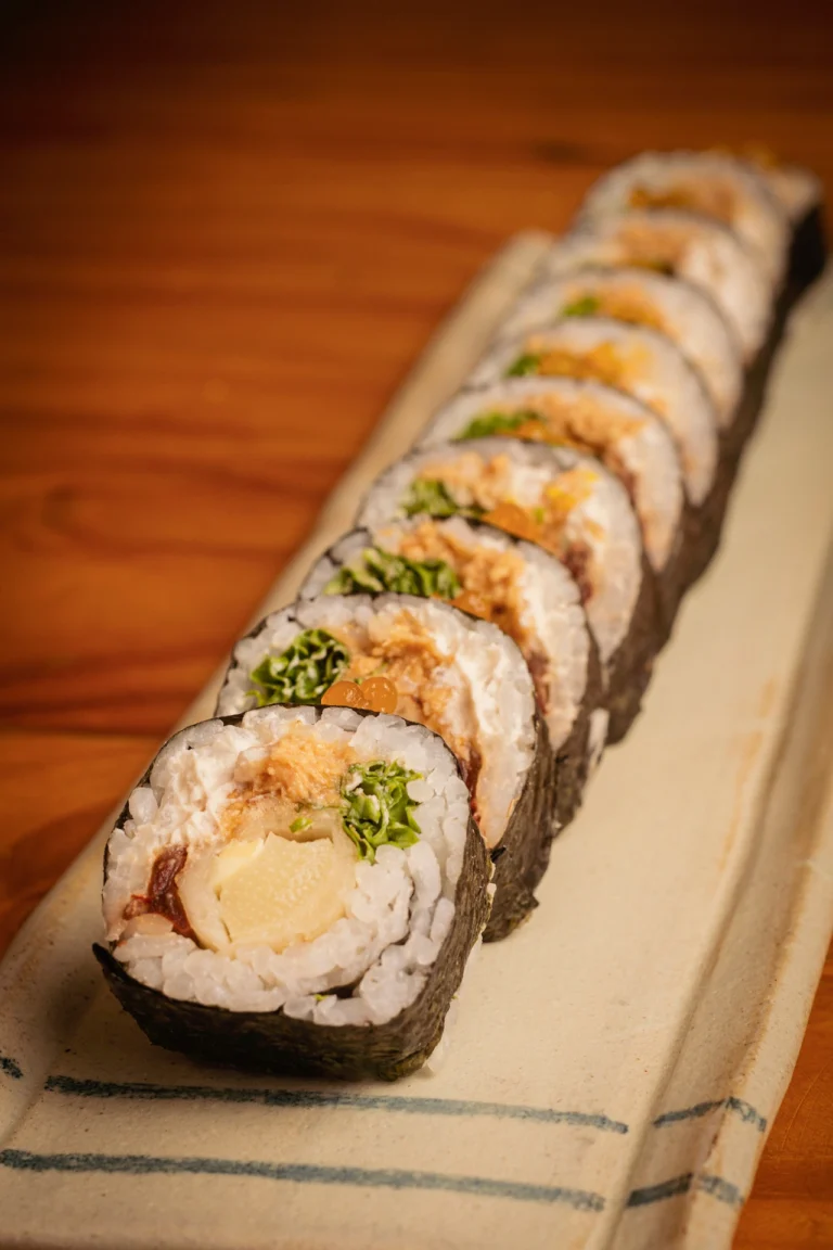 Fotografía gastronómica lateral de maki vegano con relleno de vegetales y esferas naranjas sobre bandeja con lino — Jose Fonseca Medellín
