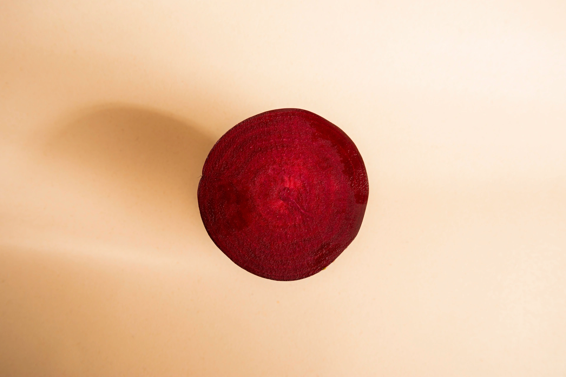 Fotografía gastronómica cenital minimalista de media remolacha sobre fondo crema con sombra lateral — Jose Fonseca Medellín