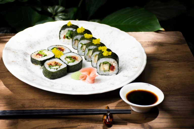 Fotografía gastronómica de sushi vegano con huevas amarillas en plato redondo blanco con palillos y salsa soya — Jose Fonseca Medellín