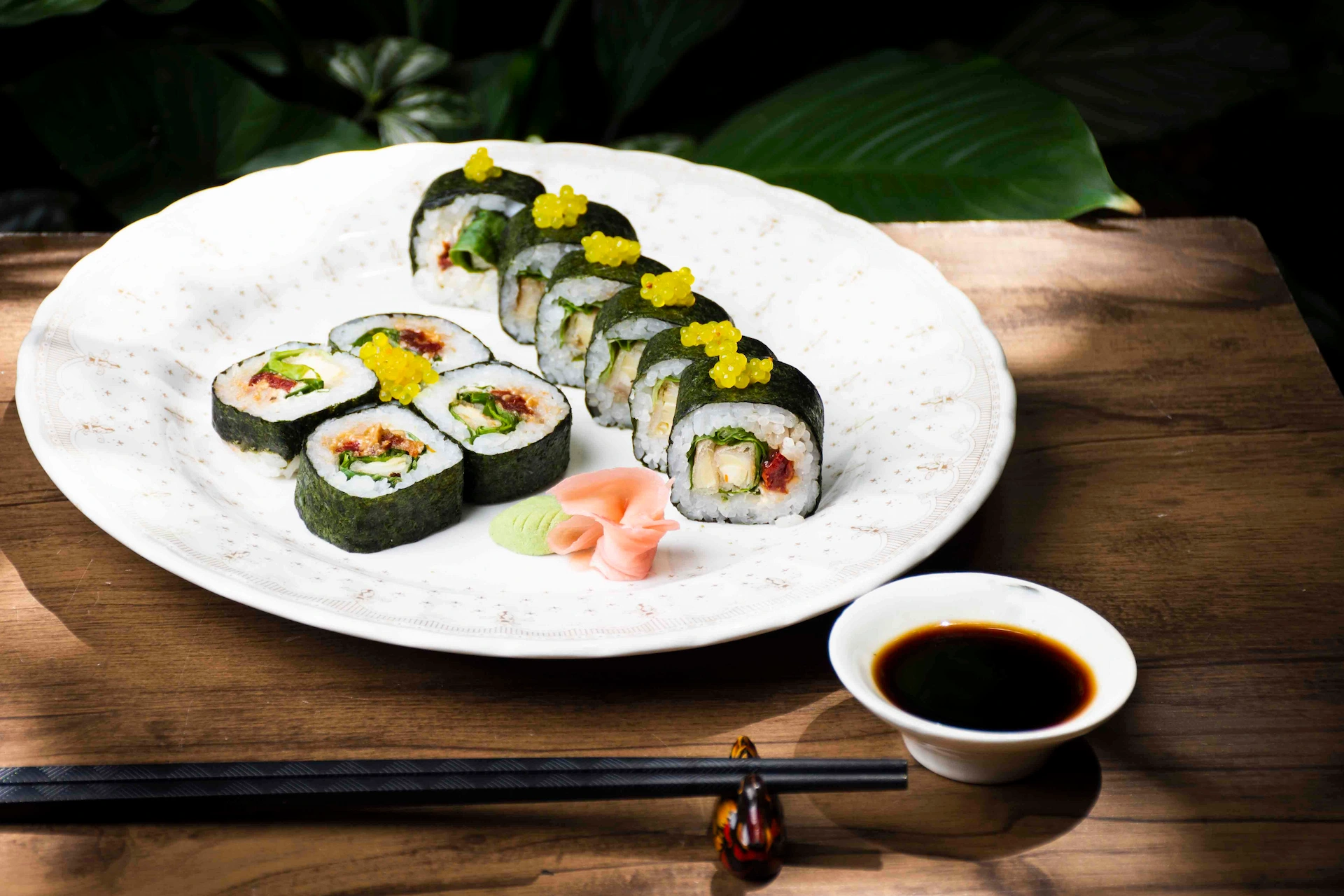 Fotografía gastronómica de sushi vegano con huevas amarillas en plato redondo blanco con palillos y salsa soya — Jose Fonseca Medellín