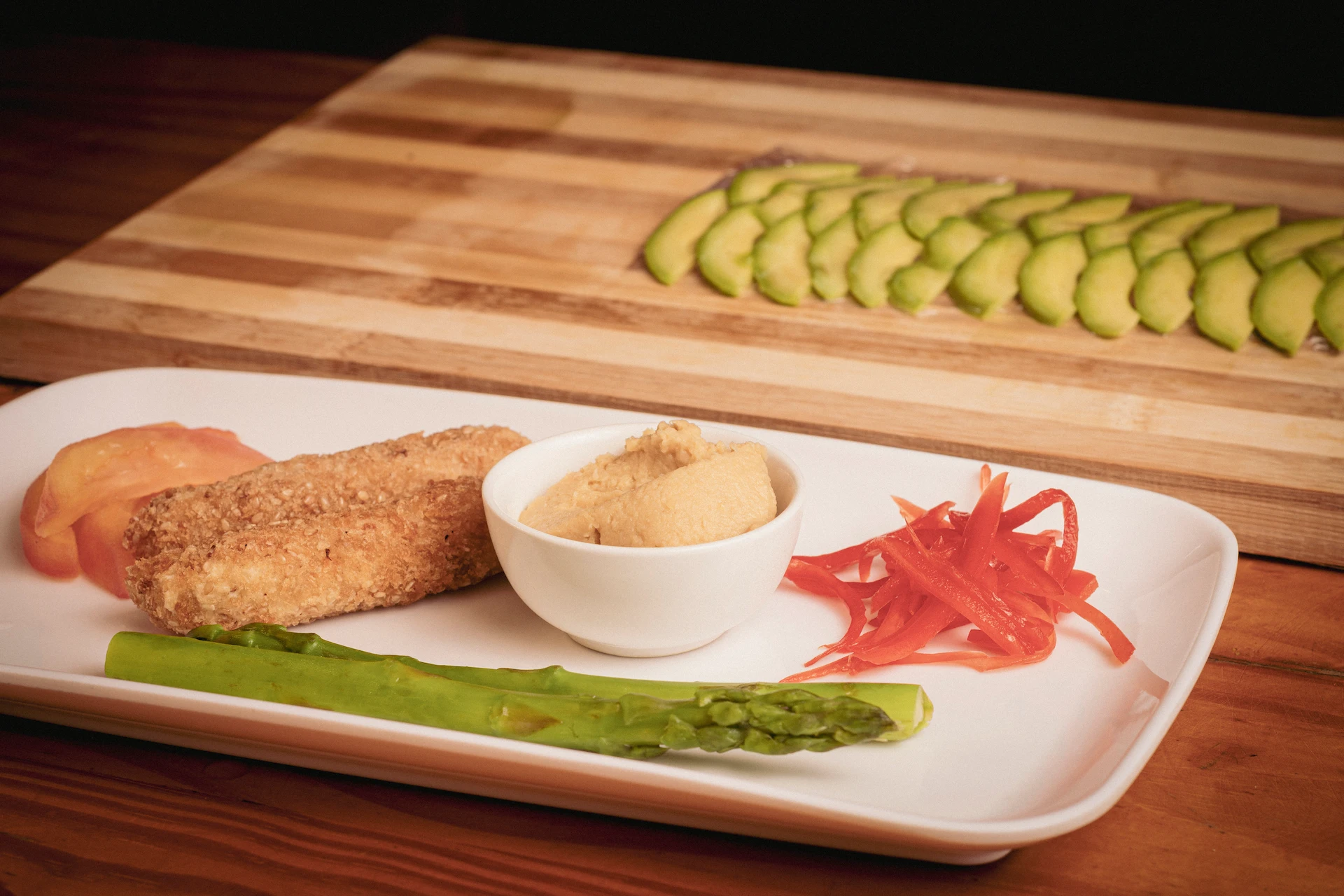 Fotografía gastronómica de tofu crocante, hummus, espárrago y pimentón encurtido en plato blanco rectangular — Jose Fonseca Medellín