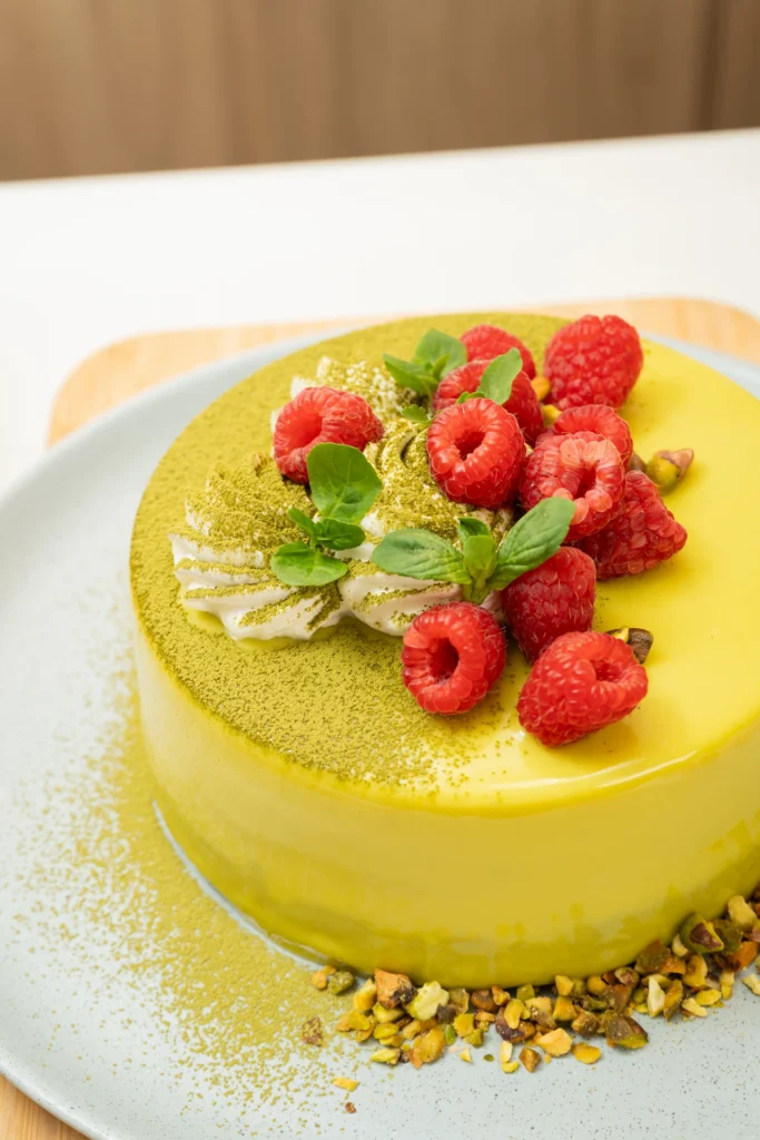 Fotografía gastronómica de torta espejo amarilla con frambuesas, pistachos y polvo de matcha — Jose Fonseca Medellín