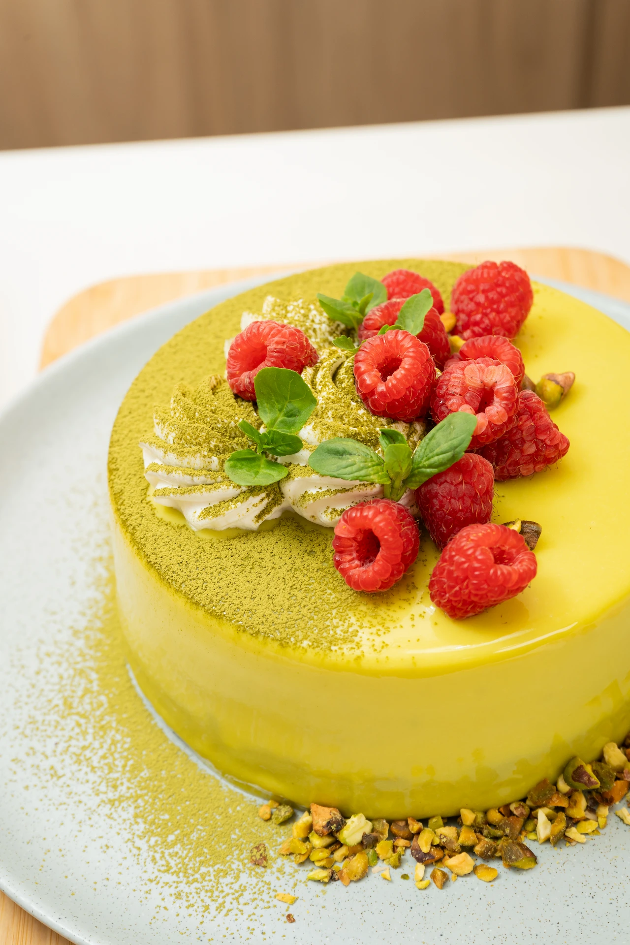 Fotografía gastronómica de torta espejo amarilla con frambuesas, pistachos y polvo de matcha — Jose Fonseca Medellín