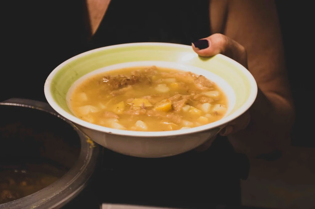 Manos de Gloria Inés sosteniendo la sopa de tortilla — Sin Receta, Jose Fonseca