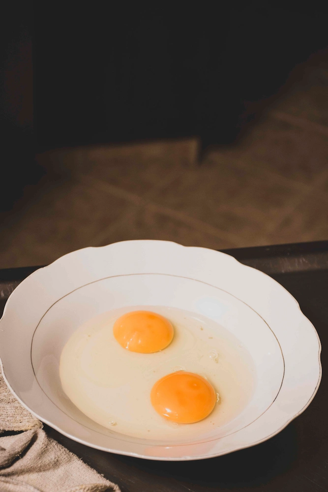 Dos yemas de huevo sobre plato blanco, preparación tortilla colombiana — Sin Receta